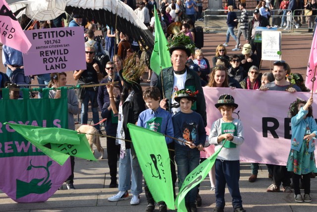 Chris Packham stands with children on the royal rewild procession outside Buckingham Palace